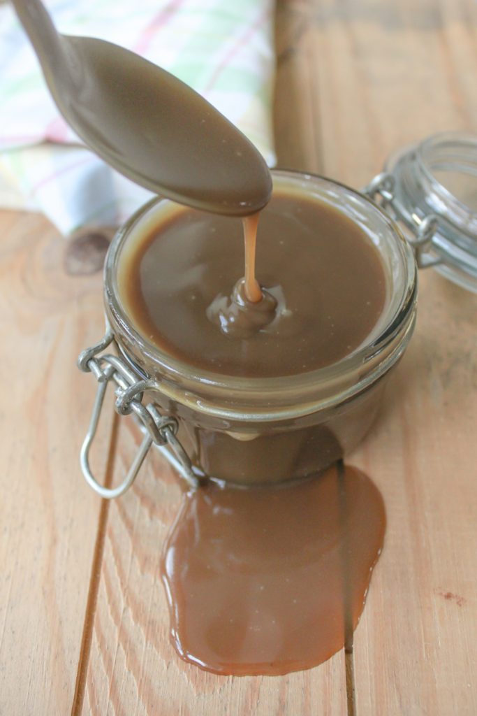 spooning caramel in a jar