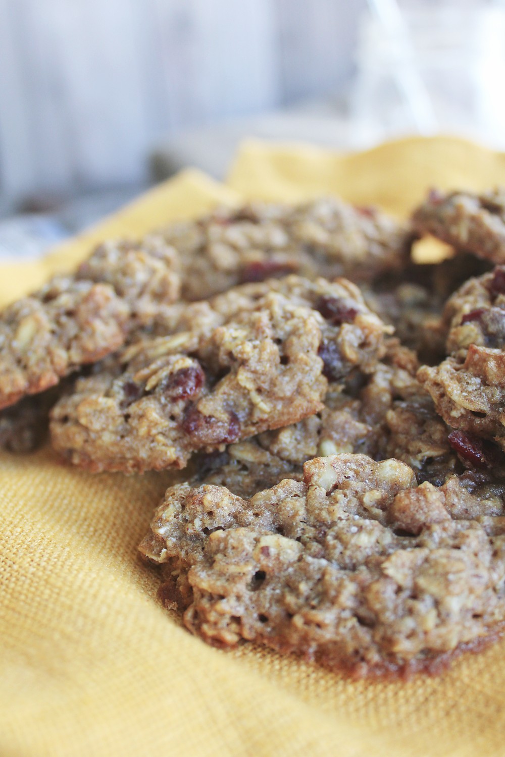 Close-up of soft chewy healthy oatmeal cookies showing texture with oats, craisins, and walnuts on yellow napkin